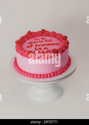 Rosafarbener, glänzender, eleganter Kuchen mit lustigem Schriftzug. Feier-Cupcake. Humor im Lebensmittelkonzept. Sei stark, sei böse. Stockfoto