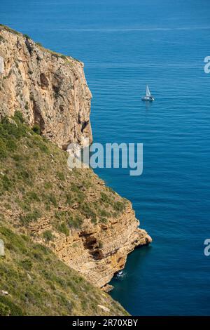 Segelboot, das an der Küste von Cova dels Òrguens in Spanien fährt Stockfoto