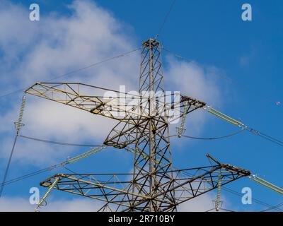 Nahaufnahme des oberen Teils eines Strompylons vor einem blauen Himmel in Großbritannien. Stockfoto