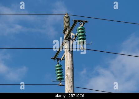 Hölzerne Strommasten mit Glasisolatoren zwischen den Kabeln. UK Stockfoto