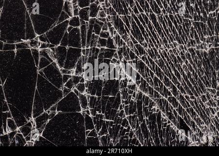 Verschmutztes Glas, das in eine große Anzahl von Teilen zerbrochen ist, ein Stück Glas mit vielen Rissen und gebrochenen Teilen Stockfoto