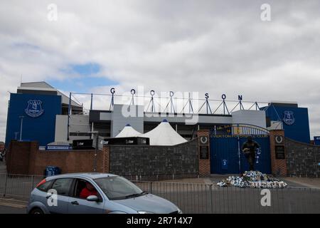 Das Park End Tor zum Goodison Park, dem Stadion des FC Everton, mit der Dixie Dean Statue und Blumenauszeichnungen im Vordergrund. Ein Auto kommt vorbei. Stockfoto