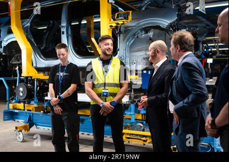 Köln, Deutschland. 12. Juni 2023. Bundeskanzler Olaf Scholz (3. von links, SPD) und William Clay Ford (4. von links), CEO von Ford, sprechen mit Mitarbeitern bei der Zeremonie vor der Eröffnung des Ford Cologne Electric Vehicle Center. Im Hintergrund befindet sich ein Ford Explorer in der Baugruppe. Das Kölner Werk wird Fords erstes EV-Zentrum in Europa sein. Kredit: Marius Becker/dpa/Alamy Live News Stockfoto