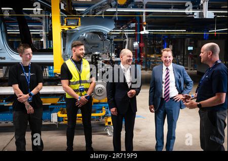 Köln, Deutschland. 12. Juni 2023. Bundeskanzler Olaf Scholz (3. von links, SPD) und William Clay Ford, CEO von Ford, sprechen bei der Eröffnungszeremonie des Ford Cologne Electric Vehicle Center mit Mitarbeitern. Im Hintergrund befindet sich ein Ford Explorer in der Baugruppe. Das Kölner Werk wird Fords erstes EV-Zentrum in Europa sein. Kredit: Marius Becker/dpa/Alamy Live News Stockfoto