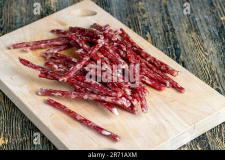 Dünne Schweinewurst mit Gewürzen, trockene dünne Wurst aus getrocknetem Schweinefleisch mit Gewürzen und Schmalz Stockfoto