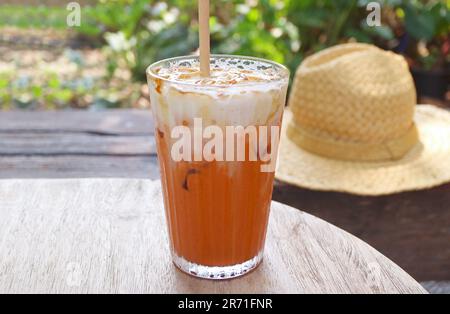 Ein Glas köstlicher thailändischer Eistee auf einem Gartentisch Stockfoto