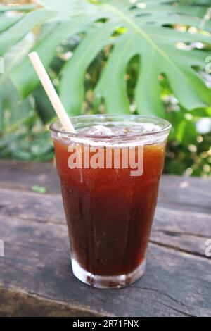 Ein Glas gekühlten Eiskaffee isoliert auf einem Gartentisch aus Holz Stockfoto