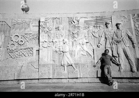 Shanghai China 2000. Das Denkmal für die Helden der Völker in den Huangpu-Gärten wurde am 31. Dezember 1988 begonnen und am 27. Mai 1994, dem 45. Jahrestag der Befreiung Shanghais, fertiggestellt. Ein dreiteiliger Betonpylon erhebt sich aus einer versunkenen Arena, in der sich ein 120 Meter langer Fries befindet. In sieben Abteilungen gegliedert, erinnert sie an die Kämpfe der Menschen zwischen 1840 und 1949. Hier im letzten Panel begrüßen die Menschen von Shanghai die Volksbefreiungsarmee, die PLA. Dies ist eine beliebte Gegend für Fußball und Sonnenbaden. 2000er Jahre HOMER SYKES Stockfoto