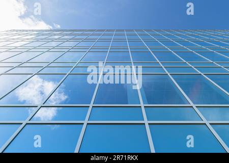 Ein kleines Foto von der Seite eines hohen Gebäudes aus Glas, das den blauen bewölkten Himmel reflektiert Stockfoto