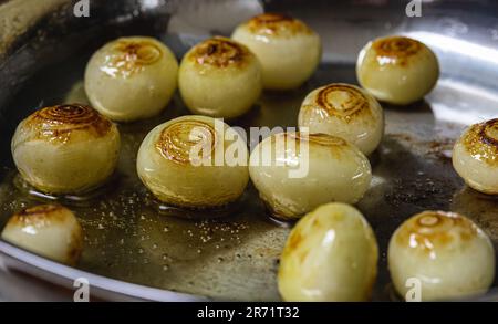 Kleine Perlzwiebeln, die in einem Topf geröstet werden, oben, Nahaufnahme. Stockfoto