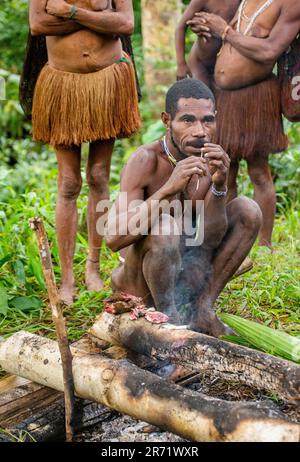 Männer des Korowai-Stammes bereiten Essen zu. Stamm der Korowai (Kombai, Kolufo). Stockfoto