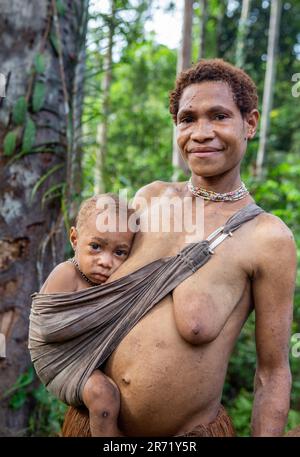 Frau des Korovai-Stammes mit einem Kind. Stamm der Korowai (Kombai, Kolufo). 10. Juni 2016 in Onni Village, Neuguinea, Indonesien Stockfoto