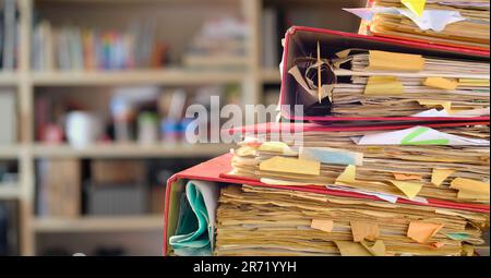 Unordentliche Akten, Bürokratie, Bürokratie, Laminierung, Geschäftskonzept. Verschwommenes Büroinnere im Hintergrund. Stockfoto