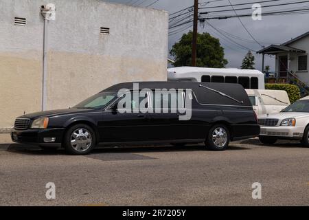 Ein schwarzer und weißer Cadillac Hearse parkt auf der Straße vor einem Gebäude in Südkalifornien. Stockfoto