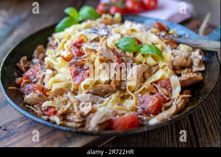Pasta mit Hähnchenfleisch, Tomaten, roten Zwiebeln, Kräutern und Parmesankäse Stockfoto