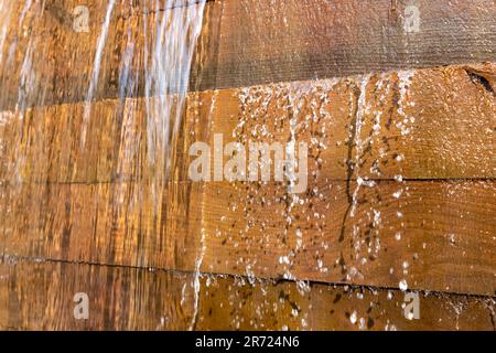 Nahaufnahme von Wasser, das durch einen Holzplanken-Damm tropft. Stockfoto