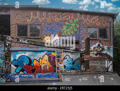 Kopenhagen, Dänemark - 14. September 2010: Christiania freetown. Farbenfrohe Graffiti füllt die Außenwand des Lagerhauses unter blauer Wolkenlandschaft. Ein bisschen Stockfoto