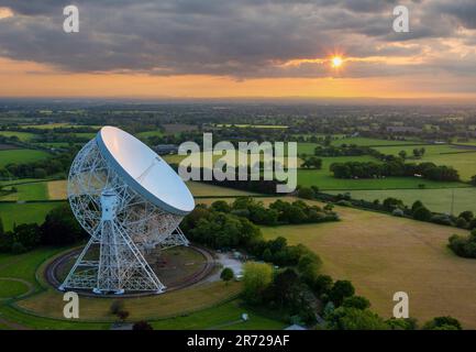 Goostrey, Cheshire, Vereinigtes Königreich. Der Sonnenuntergang spiegelt sich vor dem Lovell Telescope in der Jodrell Bank, Cheshire, wider. Luftbild. 22. Mai 2023 Stockfoto