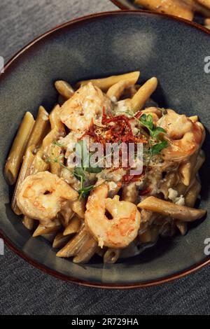Eine Keramikschüssel mit einem köstlichen Teller Shrimp Rigatoni Pasta mit Saffron Stockfoto