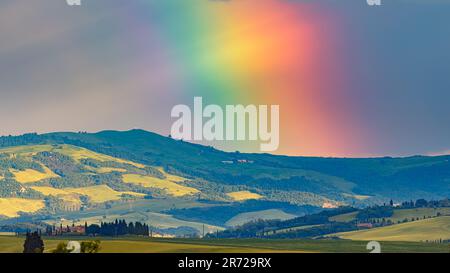 Ein 16:9-Foto einer Landschaft in der Toskana mit einem riesigen Regenbogen im Abendlicht. Das Foto wurde in Val d'Orcia in Mittelitalien aufgenommen. Stockfoto