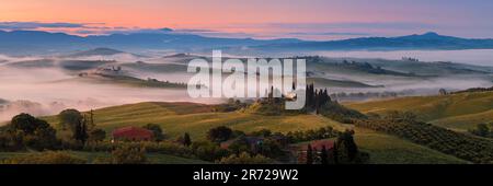 Ein breites 3x1-Panoramabild des berühmten Podere Belvedere im Morgenlicht mit etwas Nebel über dem Land im Herzen der Toskana. Belvedere liegt dazwischen Stockfoto