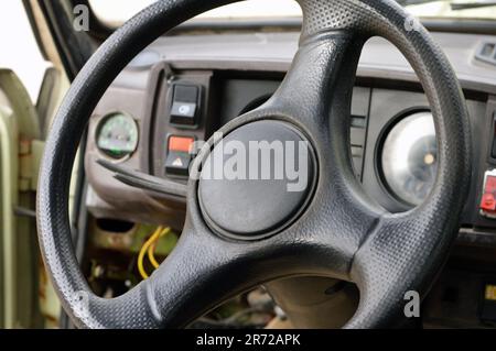 Altes Armaturenbrett des Fahrzeugs der 70er Jahre mit Tachometer, Tasten für Beleuchtung und Ventilator, Lederlenkrad, selektiver Fokus auf altem Jahrgang C. Stockfoto