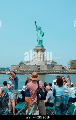 New York City, USA - 22. Mai 2023: Touristen an Bord eines Tourboots, die vor der Freiheitsstatue auf Liberty Island, New York, Stockfoto