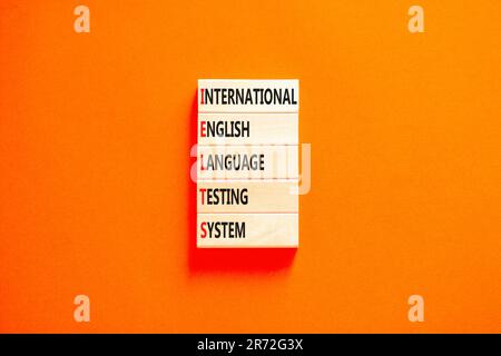 IELTS-Symbol. Konzeptbegriffe IELTS internationales englischsprachiges Prüfsystem auf Holzblock. Wunderschöner orangefarbener Hintergrund. Business IELTS internati Stockfoto