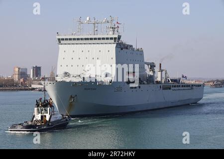 Der Schlepper SD SCHWELGT vor dem Royal Fleet Hilfslandeschiff Dock RFA MOUNT BAY, wenn das Schiff der Bay Class vom Marinestützpunkt ablegt Stockfoto