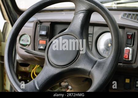 Altes Armaturenbrett des Fahrzeugs der 70er Jahre mit Tachometer, Tasten für Beleuchtung und Ventilator, Lederlenkrad, selektiver Fokus auf altem Jahrgang C. Stockfoto