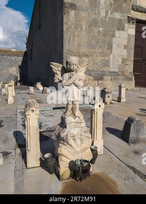 Eine Engel- oder Engelskulptur auf einem Grab auf dem Friedhof in der Nähe des Pieve di San Giovanni, Campiglia Marittima, in der Provinz Livorno, Italien Stockfoto