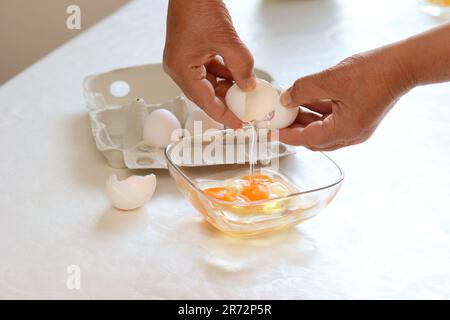 Eine Frau knackt Eier in Eine Schale Stockfoto