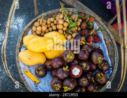 Blick von oben auf farbenfrohe, frische tropische Früchte im Korb an der Vietnam Local Street, einschließlich Mango, Litschi, Longan und Mangoteen Stockfoto