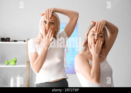 Junge Frau mit Physiotherapeutin, die Gesichtsaufbauübungen im Rehabilitationszentrum macht Stockfoto