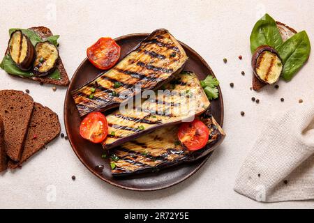 Zusammensetzung mit köstlichen gegrillten Auberginen auf hellem Hintergrund Stockfoto