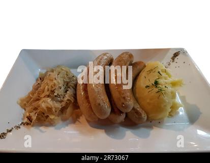 Einzelbild von gebratenen Würsten mit Sauerkraut und Kartoffelpüree auf einem Teller Stockfoto