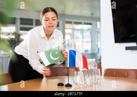 Vorbereitung auf Geschäftsverhandlungen - Frau setzt kleine Flaggen von Ländern Frankreichs und Pakistans auf den Tisch Stockfoto