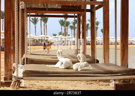 Schwingen Sie in einem Strandbungalow an der Küste mit Handtüchern in Schwanenform. Sommerurlaub und Entspannung auf dem Meer Resort Stockfoto