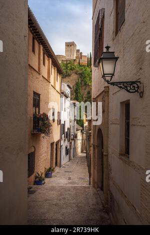 Straße des traditionellen Albaicin-Viertels mit Alhambra-Türmen im Hintergrund - Granada, Andalusien, Spanien Stockfoto