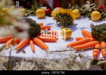 Äpfel, Karotten und Brokkoli auf einem weißen Tisch mit einer weißen Tischdecke Stockfoto