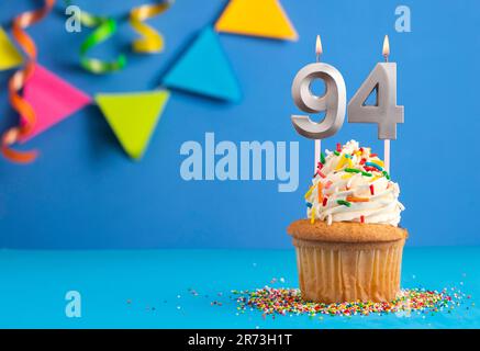 Kerze Nummer 94 - Kuchen zum Geburtstag auf blauem Hintergrund Stockfoto