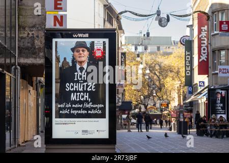 Bild eines Werbespots, ein PSA der deutschen Gesundheitsbehörden, der ältere Generationen um einen Covid-Impfstoff bittet, der im Stadtzentrum von Dor aufgenommen wird Stockfoto