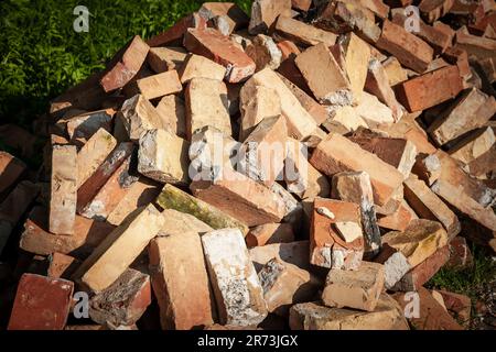 Bild von roten Tonsteinen im Stapel, gebraucht und beschädigt, gestapelt, darauf wartend, recycelt zu werden. Stockfoto