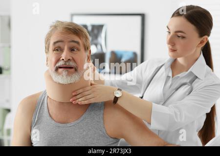 Orthopädin, der das Halsband am Hals des Patienten in der Klinik anlegt Stockfoto