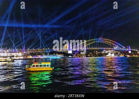 VIVID Sydney 2023. Lichtshow im Hafen von Sydney. Hafenbrücke Lasershow und Boote. Stockfoto