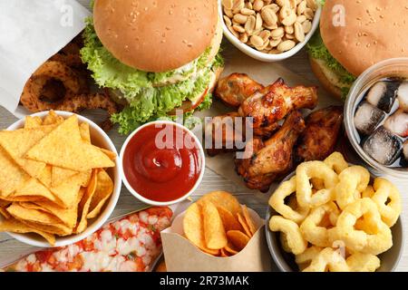 Pommes Frites, Burger und anderes Fast Food auf weißem Holztisch, flach liegend Stockfoto