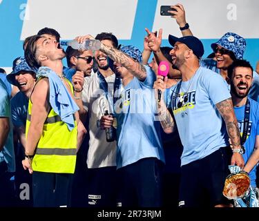 Manchester, Großbritannien. 12. Juni 2023. Kalvin Phillips gießt einen Drink in Jack Grealish's Mund, während die Spieler während ihrer Treble Winning Victory Parade, die im Rathaus in Manchester endet, zusehen. Foto: 12. Juni 2023. Das Bild sollte lauten: Gary Oakley/Sportimage Credit: Sportimage Ltd/Alamy Live News Stockfoto