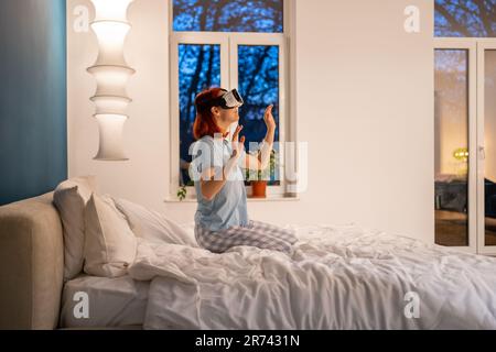 Aufgeregte, lächelnde Frau mit virtueller Brille, die sich einen Film ansieht, der Videospiele spielt. Stockfoto