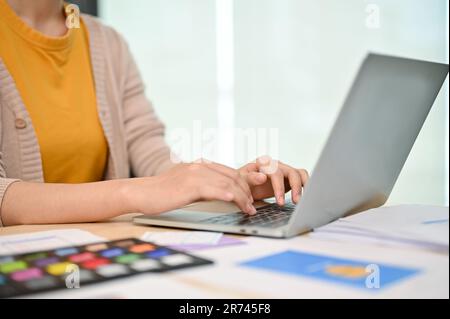 Zugeschnittenes Bild einer Grafikdesignerin oder UI-Entwicklerin, die an ihrem Laptop an ihrem Schreibtisch im Büro arbeitet. Stockfoto