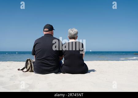 Ein Paar sitzt am Ostseestrand in der Nähe von Kühlungsborn und genießt den Sommertag im Urlaub Stockfoto